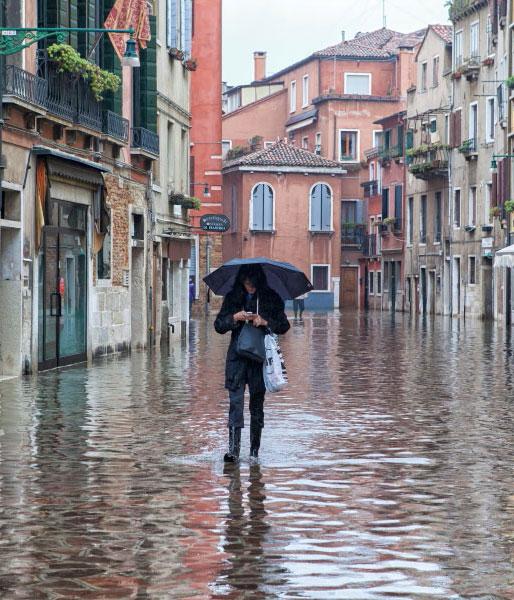 lady with umbrella walking down flooded street