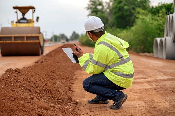 Man in high viz jacket on radio talking with road building team